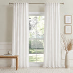 Off-white cotton-linen curtains with pleated header hanging on a window rod