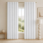 White blackout curtains with vertical pleats and metal grommets, hanging across the window.