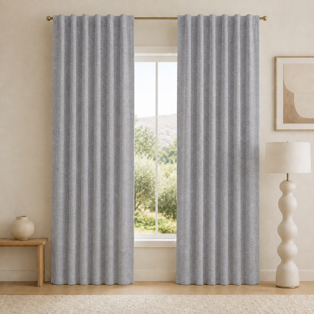 Medium gray blackout curtains with evenly spaced pleats and metal grommets at the top.