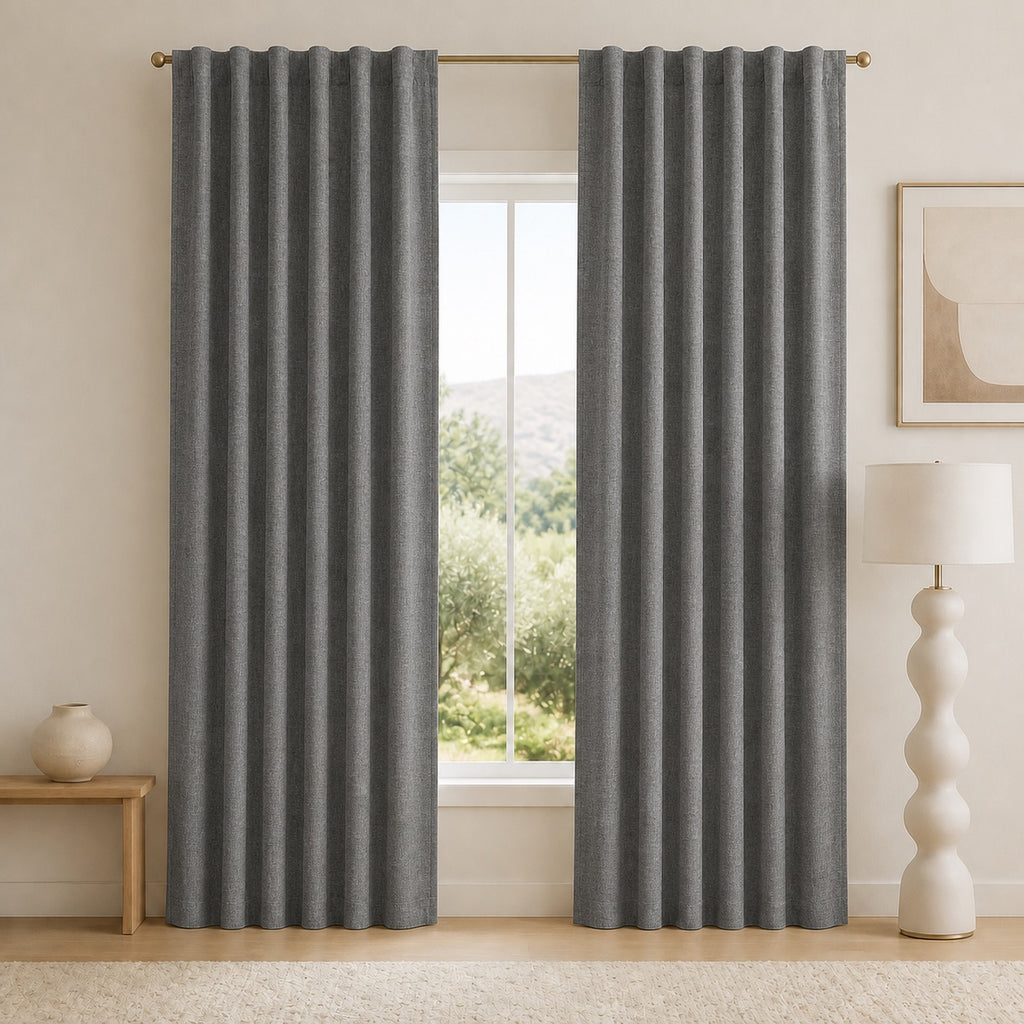 Dark gray blackout curtains with vertical pleats and grommets, shown from a straight-on angle.
