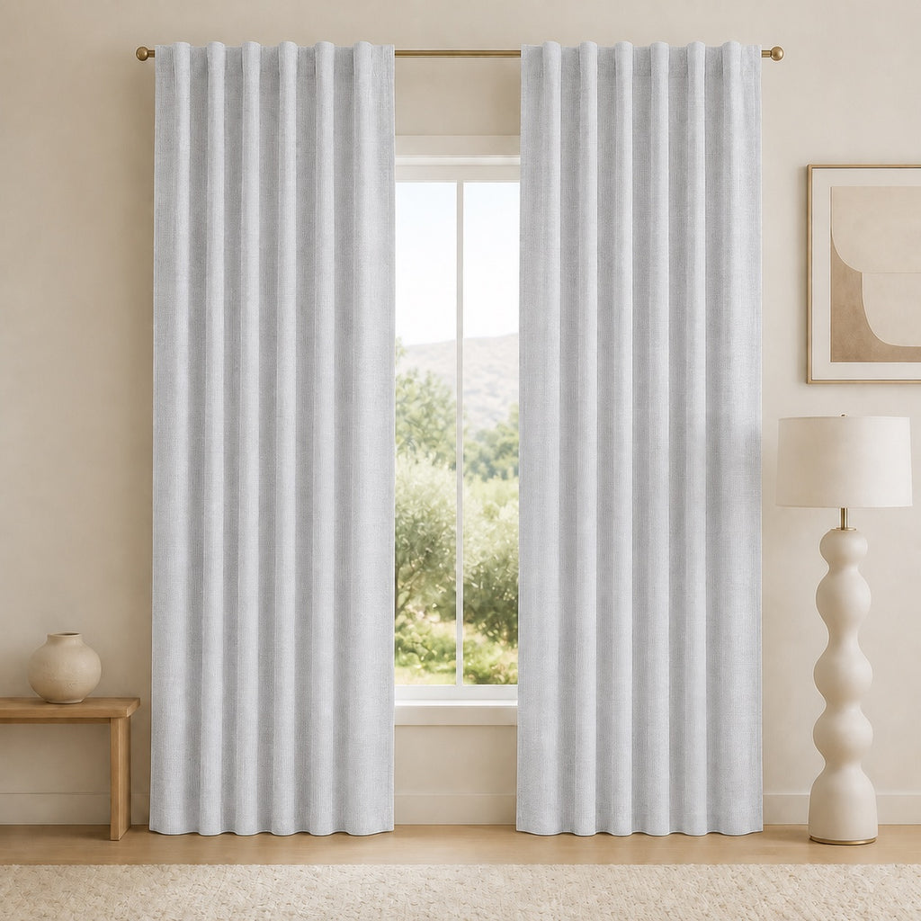 Light gray blackout curtains with vertical pleats and grommet top, open window view behind.