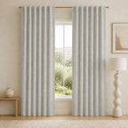 Light gray blackout curtains with grommet top and tall pleats, centered in front of window.