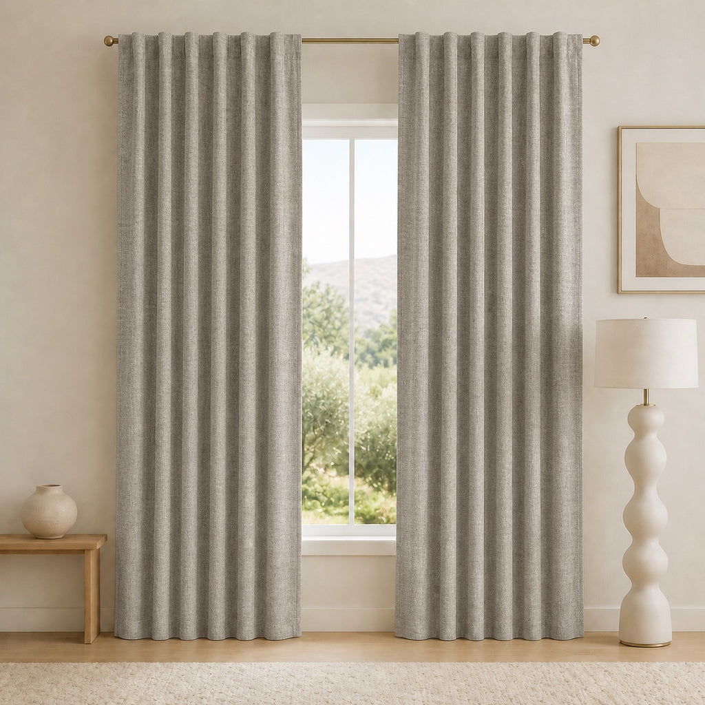 Mid-gray blackout curtains with grommet top and deep vertical pleats, mounted on a rod.
