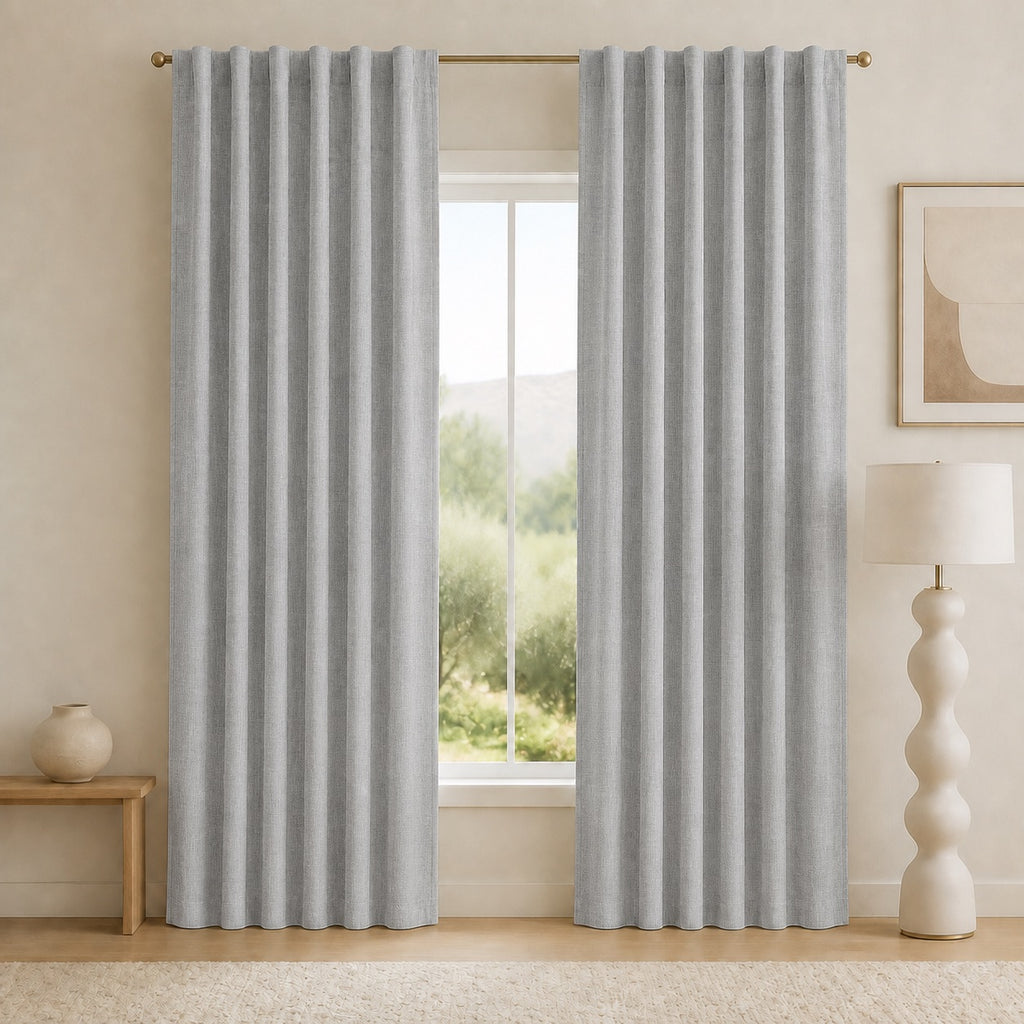 Medium dark gray blackout curtains with tall pleats and metal grommet headers, hanging evenly.