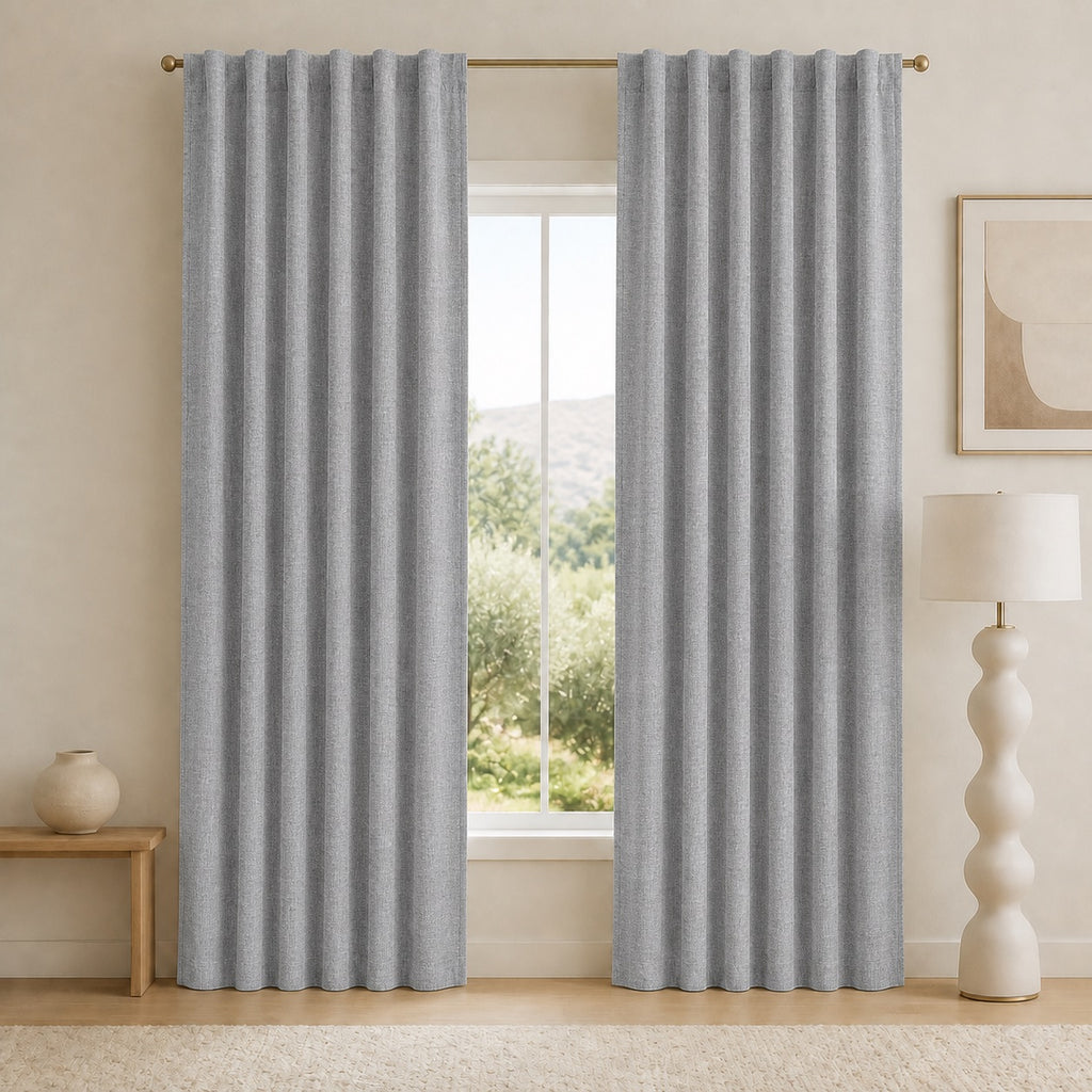 Medium gray blackout curtains with vertical pleats and grommets, hanging side by side.