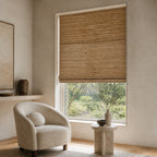 Warm tan woven bamboo roller shade with denser horizontal weave pattern over a window.
