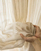 Hands adjusting sheer vertical stripe curtain, showing lightweight linen-blend texture.