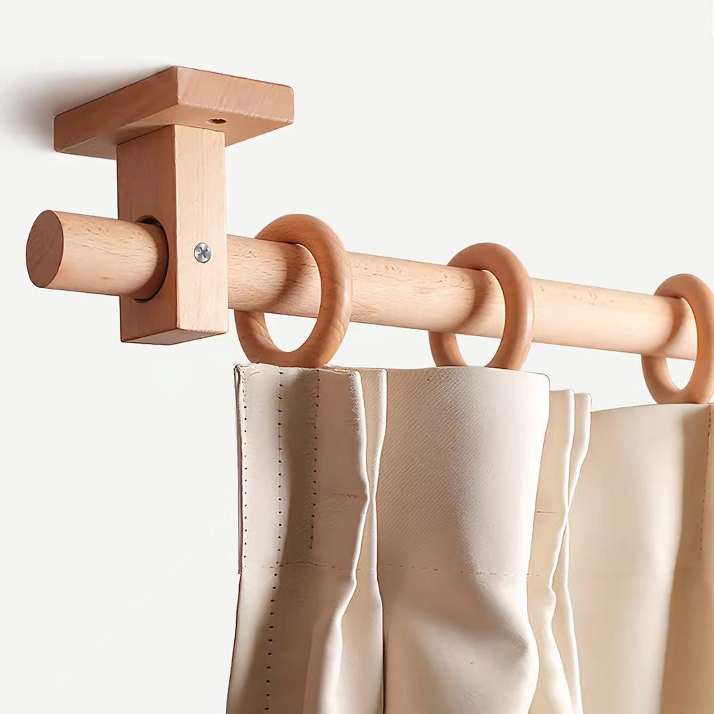 Beech-toned curtain rod with wall bracket and ring finials holding off-white panels